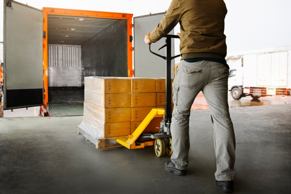 Workers Unloading Packaging Boxes on Pallets into The Cargo Container